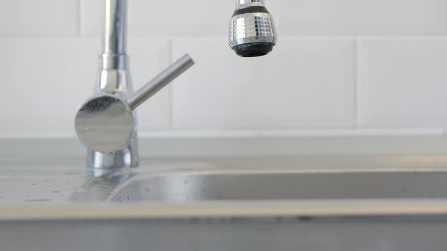 Man Throwing a Glass of Fresh Water in the Kitchen Sink.