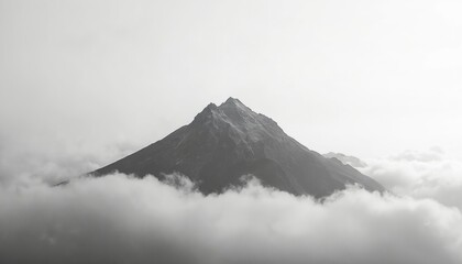 Monochrome mountain peak pierces thick cloud cover. A study of atmospheric perspective, it emphasizes the grandeur of nature. Black and white photo with dramatic sky over misty highlands. scenery.