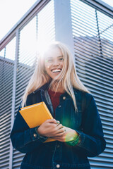 Young attractive blonde female student enjoying recreation at spring sunny urban setting during...