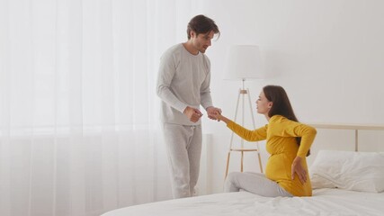 A couple interacts in their well-lit bedroom, with the woman expecting and showing discomfort while the man gently supports her, creating a warm atmosphere of anticipation. - Powered by Adobe