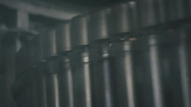 Shiny aluminum cans gliding smoothly along industrial conveyor belt, preparing for beverage filling process inside modern brewery manufacturing facility