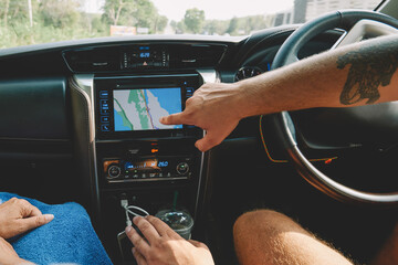 Cropped image of two tourists pointing right direction on display of modern online navigator in...