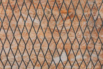 Textured Wooden OSB Board Behind Metal Mesh Fence