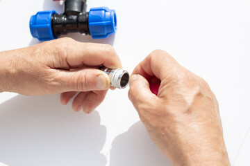 close-up of hands assembling metal threaded part with plastic fittings, winding fumka, sealing tape
