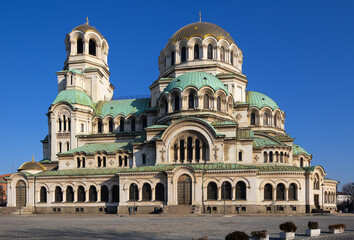 Breathtaking view of Alexander Nevsky Cathedral in Sofia, bathed in sunlight on winter day, highlighting intricate arches, gilded domes, and historic Orthodox significance.