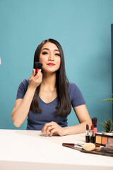 Warm and engaging beauty influencer hosting a live online makeup tutorial, showcasing various brush...