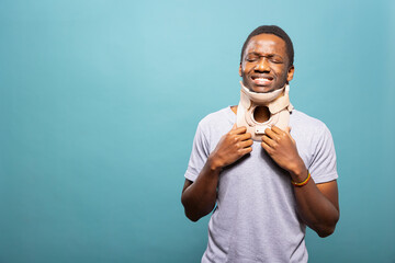 African American man wearing a cervical collar to recover from a sprained neck injury. Young...