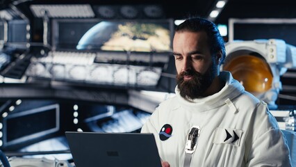 Astronaut using laptop to verify mission parameters after completing planet surface expedition....