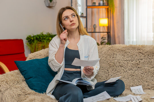 Middle-aged woman looks at bills writes notes in notebook at home staying focused and organized. Young adult girl manages expenses thoughtfully maintaining control over household budget and priorities