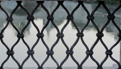 Geometric old-fashioned iron grate with the backdrop of calm river waters