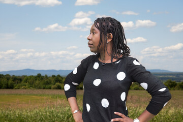 African American Woman in Her 30s with Locs in Polka Dot Blouse Against Rural Countryside