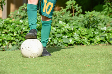 Child with foot on football as football background with copy space on grass or pitch