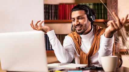 Fototapeta premium Happy Arab Man Teacher Having Virtual Lesson Via Video Call Sitting At Laptop Explaining Lecture Remotely Working From Home. E-Teaching And Distance Tutoring, Modern Online Education
