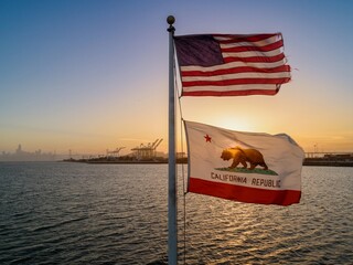 US and California flags fly over the water with the San Francisco skyline and port in the background, Oakland, Caifornia, United States