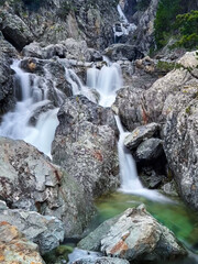 mountain stream winding through a rocky canyon, creating a stunning sequence of crystal-clear waterfalls and serene natural beauty