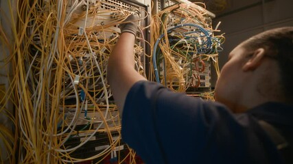 Handheld shot of young black female technician checking wires while working with server equipment - Powered by Adobe