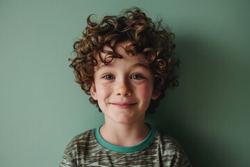 Portrait of a cute little boy with curly hair on a green background