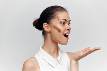 Young woman with artistic makeup expressing surprise, showcasing creativity and individuality against a neutral background.
