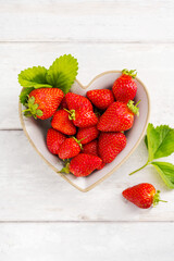 Fresh strawberries in a heart shaped bowl, top view, summer fruits. 