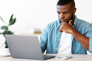 Focused African American Businessman Working With Laptop At Office, Sitting At Desk And Looking At...