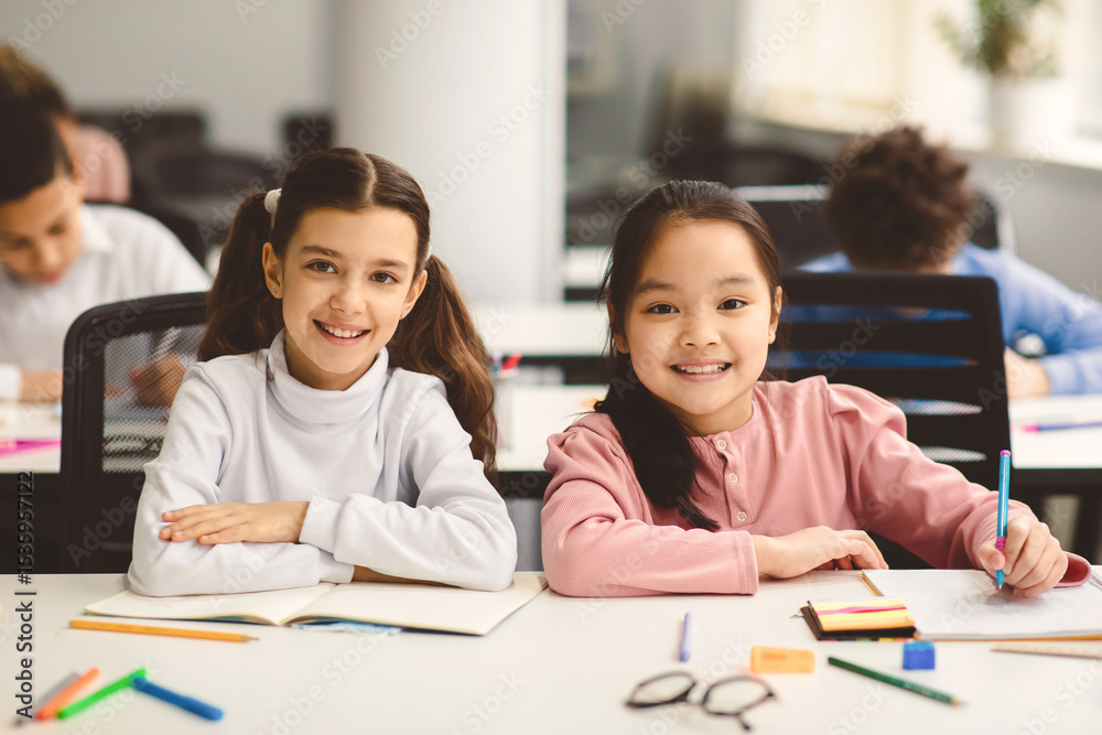 Poster education and children concept. portrait of happy smiling small girls sitting at desk in classroom a