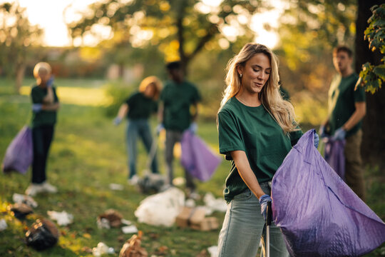 Group of volunteers cleaning park holding garbage bags - Powered by Adobe