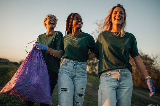Volunteers collecting garbage are walking and smiling together