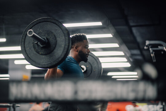 Determined athlete lifting weights in gym during intense workout