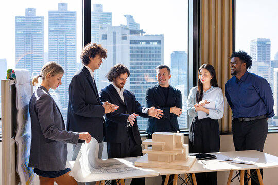 Team of diversity business people having agreement and handshake deal over new strategic strategy project on investment real estate with recognition and applause from other colleagues for partnership