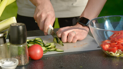 man preparing salad of onions cucumbers and tomatoes in the backyard.close-up of hands with vegetables.hands preparing salad of vegetables onions tomatoes cucumbers