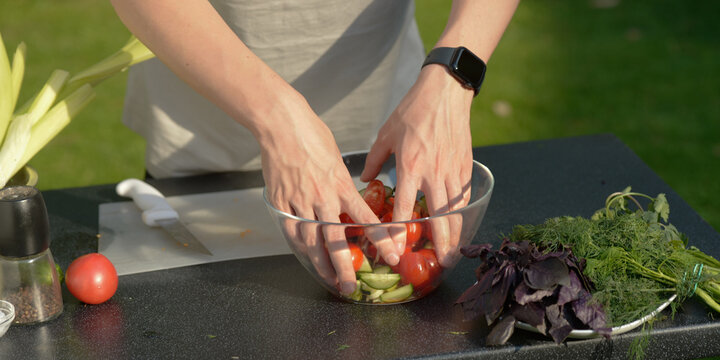 man preparing salad of onions cucumbers and tomatoes in the backyard.close-up of hands with vegetables.hands preparing salad of vegetables onions tomatoes cucumbers