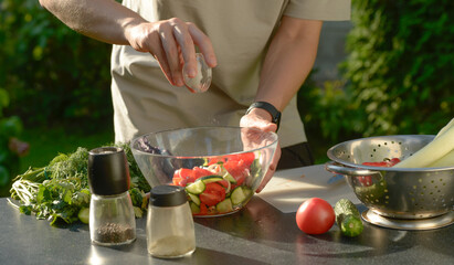 man preparing salad of onions cucumbers and tomatoes in the backyard.close-up of hands with vegetables.hands preparing salad of vegetables onions tomatoes cucumbers