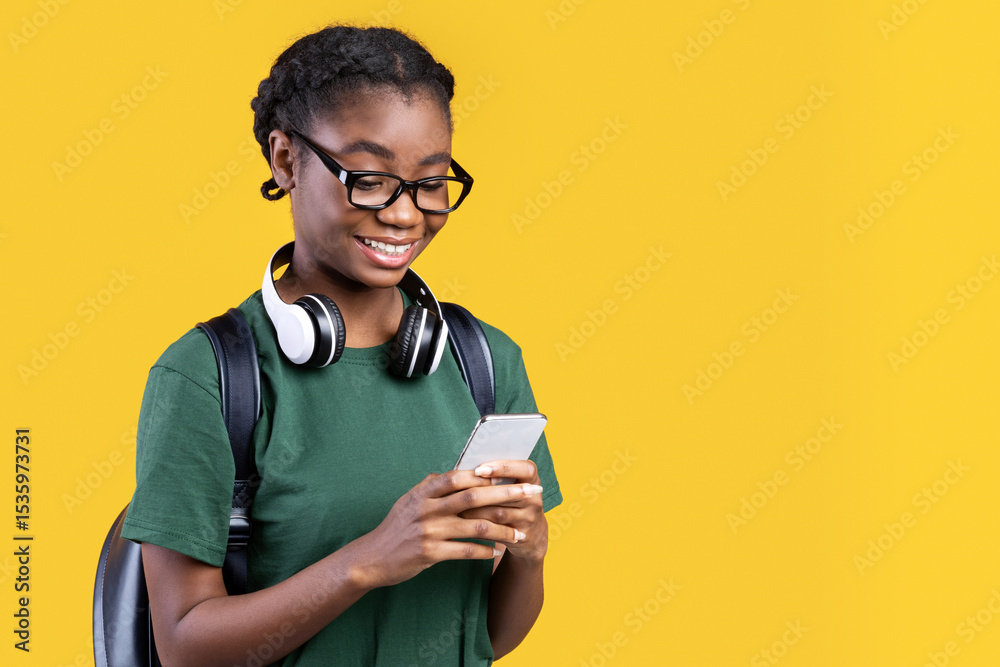 Aufkleber happy african female student using smartphone networking and texting online standing over yellow bac