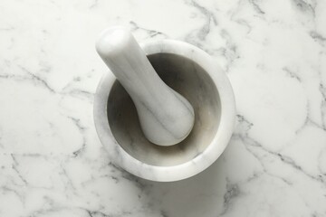 Mortar and pestle on white marble table, top view