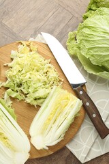 Fresh Chinese cabbages and knife on wooden table, flat lay