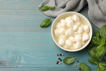 Mozzarella cheese balls with basil and peppercorns on blue wooden table, flat lay. Space for text