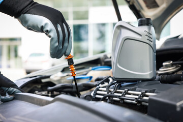 Worker checking motor oil level in car with dipstick, closeup