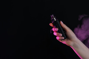 Woman using electronic smoking device in neon lights on black background, closeup. Space for text