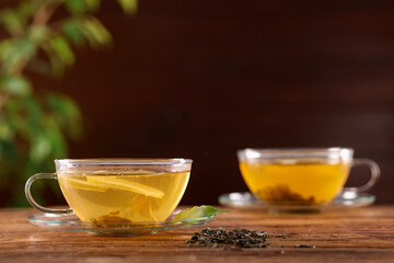 Cups of tasty green tea with lemon on wooden table, closeup