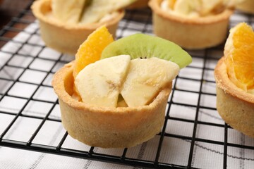 Tartlets with fruits and mint on table, closeup. Delicious dessert