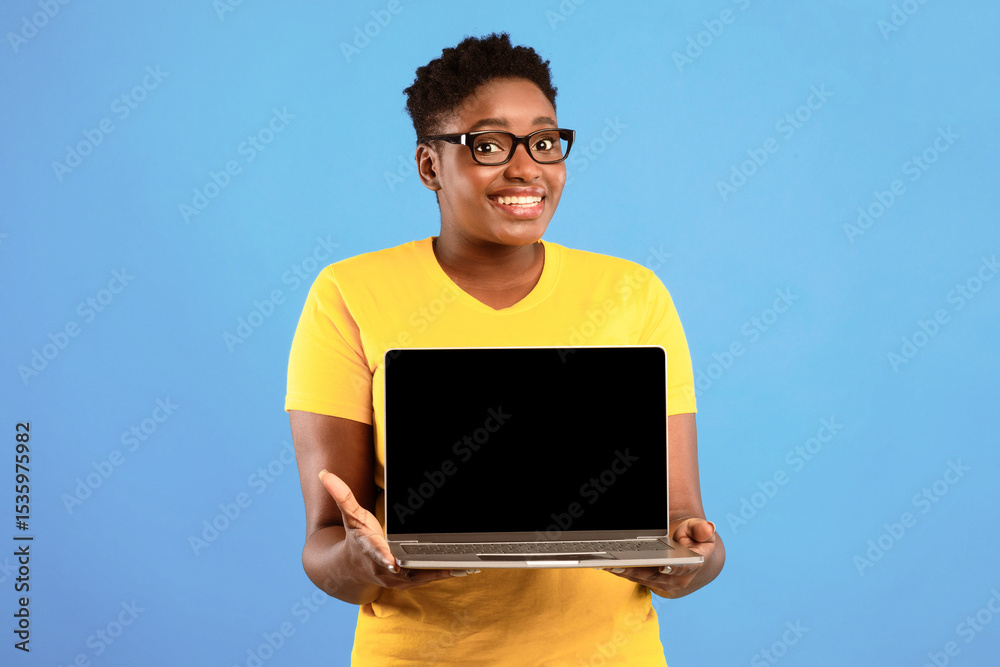 Poster smiling oversized black woman holding laptop with blank screen posing over blue studio background. l