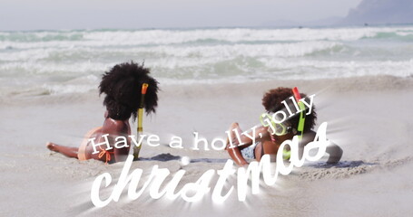 Lying siblings wearing swimwear and snorkel gear exploring shoreline at beach, with inflatable ring