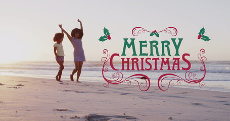 Dancing mother and daughter skipping along sunset beach, Merry Christmas holly overlay, copy space
