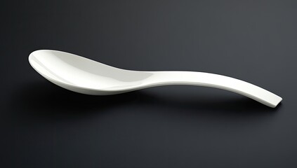A smooth, white soup spoon, angled on a dark background