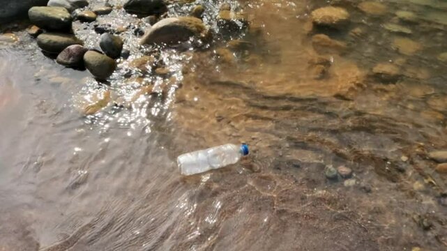 Slow motion of plastic bottle waste floating on the river bank. Source of water pollution. Ecology and environmental concept. Footage 4K 