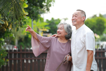 Asian elderly couple hugging each other living together in retirement. Both are smiling happily looking forward together. Health care in the elderly.