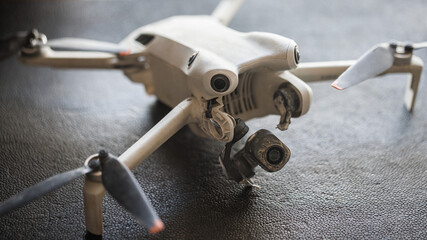 Crashed photographic drone with broken gimbal with mud and dirt. Recovered drone. Damage photographic equipment.