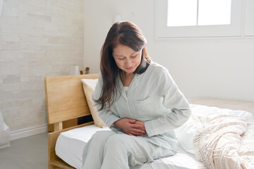 腹痛のパジャマを着た中年の女性