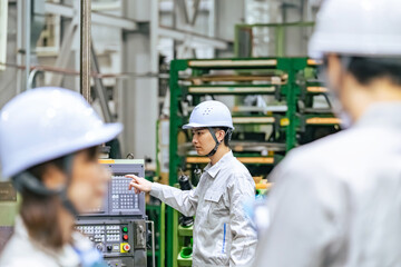 工場で操作盤で機械を操作する男性作業員
