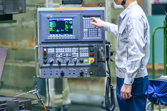 工場で操作盤で機械を操作する男性作業員